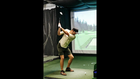 Golf practice session indoors with virtual landscape on display