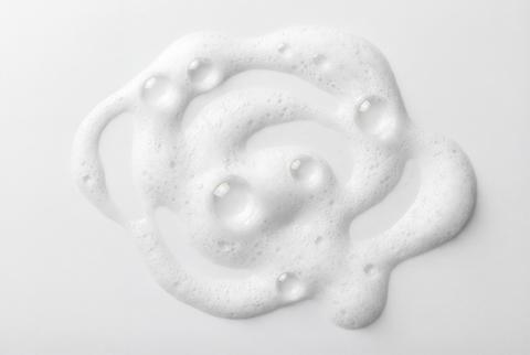 White cosmetic cleansing foam with delicate bubbles creating an abstract pattern