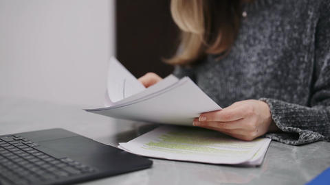 Businesswoman analyzing documents and typing on laptop