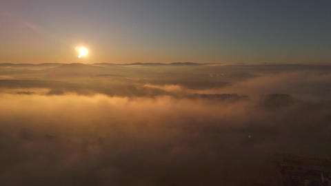 Aerial view of a sea of fog over morning countryside under clear sky with sun