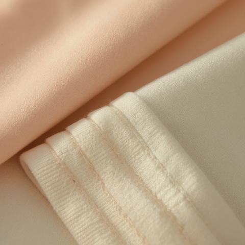 Soft peach and white fabrics layered with gentle light highlighting textures
