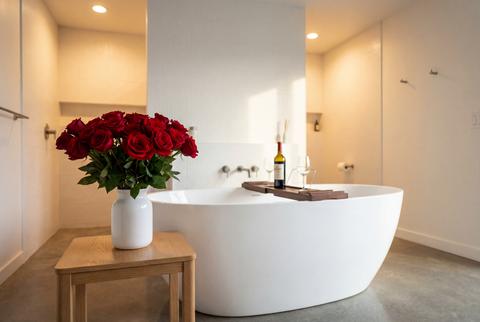 White freestanding bathtub with wine and roses in a modern bathroom