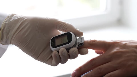 Close-up Video of Doctor's Gloved Hand Placing Pulse Oximeter on Patient's Finger