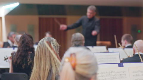 Symphony orchestra conductor directing musicians during classical music