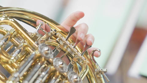Musician's hands playing valves of french horn