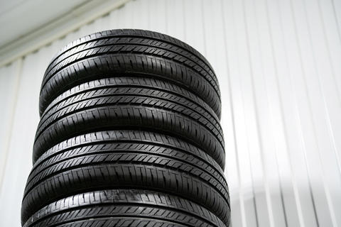 A vertical stack of new car tires