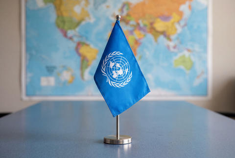 United Nations desk flag on blue gray textured surface with world map
