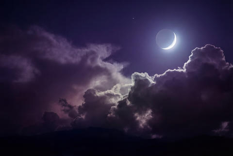 Crescent moon and bright star in a dramatic purple night sky with ethereal clouds