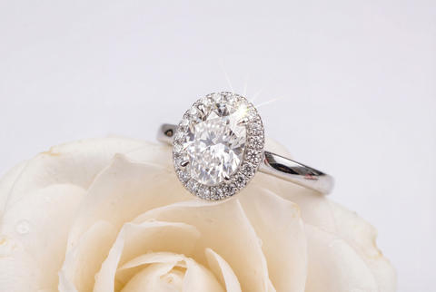 Dazzling oval diamond engagement ring with a halo of smaller diamonds on a white flower