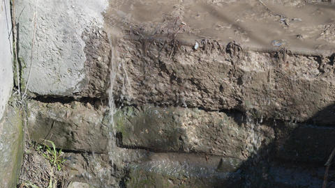 Closeup of water seepage. Scene showing slow drainage and surface weathering effects. Detailed view