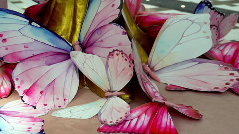 Slow camera pan across decorative pastel butterfly sculptures arranged around golden base indoors