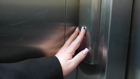 Close up of woman hand pressing elevator call button on stainless steel panel with indicator light