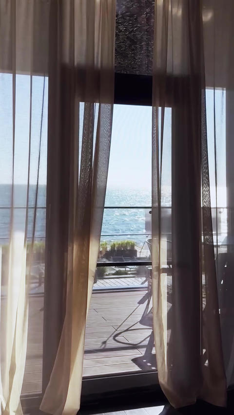 Luxury hotel room view with sea horizon through transparent curtains. Vertical video