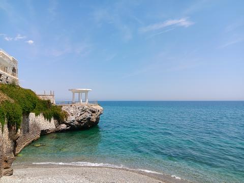 Greek beach with stone wall and white antique gazebo 02
