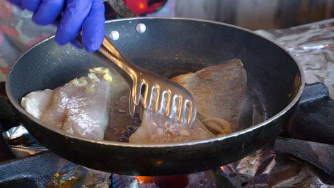 Chef frying fish in a pan in restaurant kitchen
