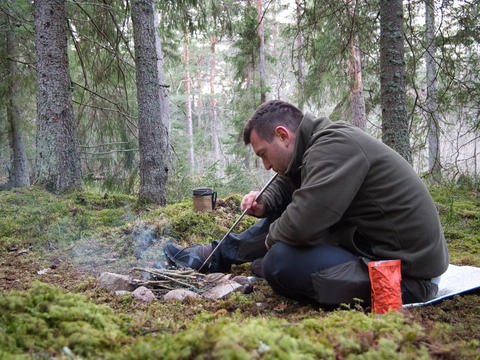 Man starting campfire in forest camping Sweden outdoor