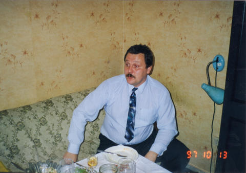 Man in shirt and tie seated at table during party 1997