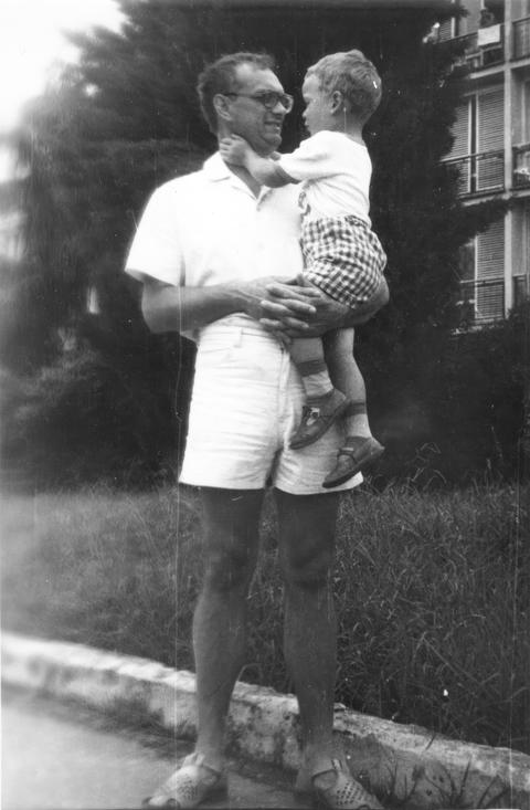 Father in white shorts holding toddler son outdoors 1980s