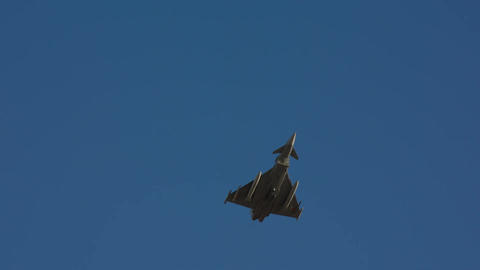 Military fighter jet rolling maneuver blue sky slow motion