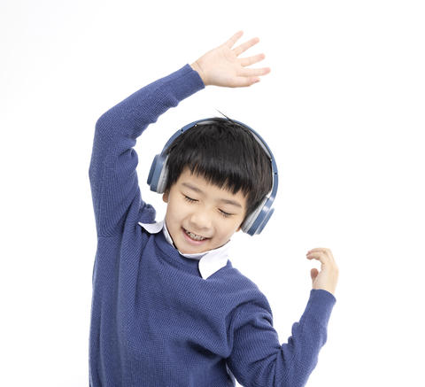 Cheerful boy in headphones singing and dancing