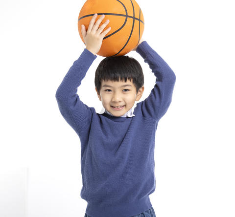 Happy boy holding basketball with his hands