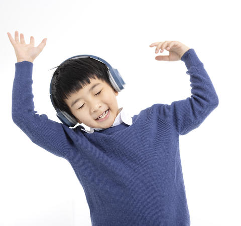 Cheerful boy in headphones singing and dancing