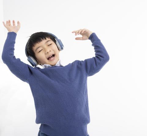 Cheerful boy in headphones singing and dancing