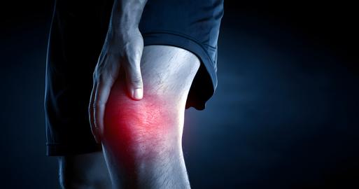 Person experiencing severe knee pain highlighted by a red glow gripping their leg in a dark mysterio