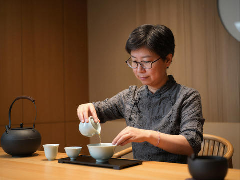Asian woman pouring tea into a bowl during a tea ceremony