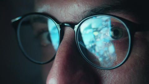 Human eyes behind glasses reflecting smartphone screen with scrolling news feed