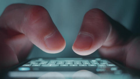 Close up texting on smartphone at night as male hand types private message using