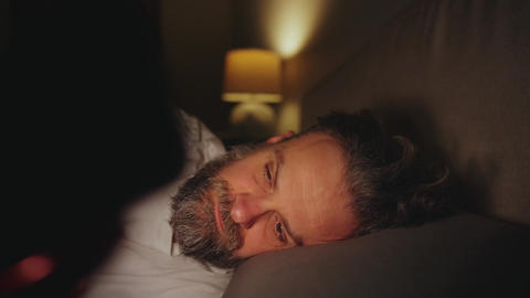 A man lying in bed using smartphone late at night