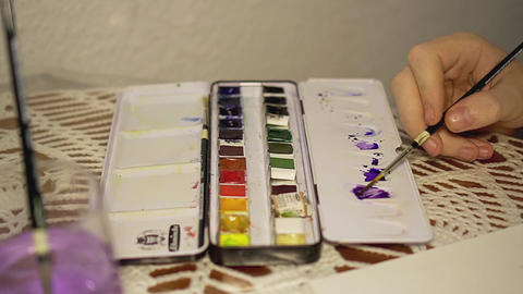 Artist mixing purple watercolor on palette, process of painting and artistic