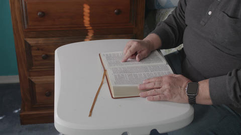 Reading a Book at a Table in the Afternoon Light With Hands Turning Pages
