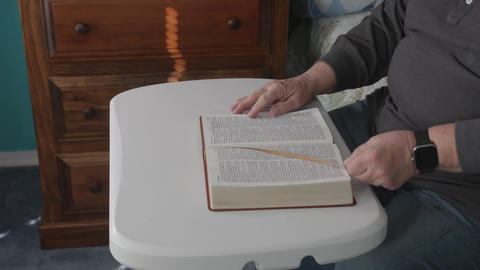 Reading a Book on a Table With Hands Turning Pages in a Simple Room During the