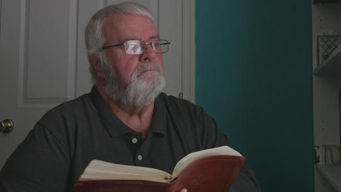 Man Reads a Book in a Room With Blue and White Walls During the Afternoon Hours