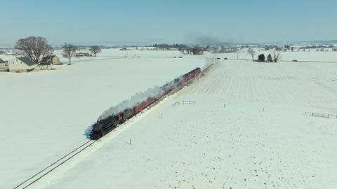Train Moves Through Snowy Fields in Winter Landscape With Farm Views Nearby