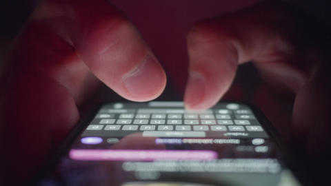 Mobile phone texting shown by male hands typing message on touchscreen keyboard