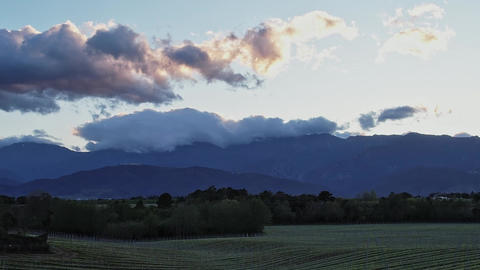 Mountains with clouds in Corsica during sunset over green fields