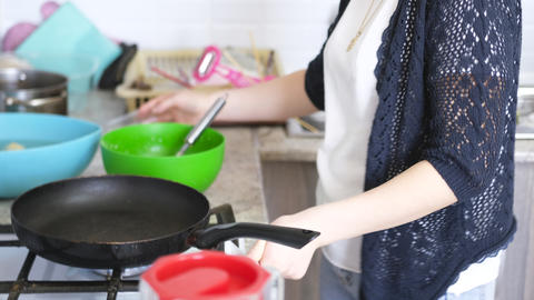 Close-up of a woman about to fry pancakes in a pan on a gas stove. Mom cooks something delicious in