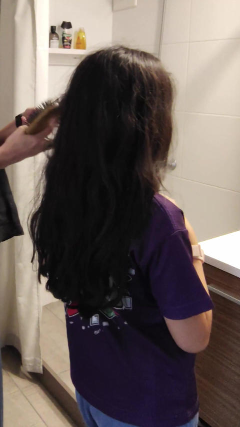 Three quarter back angle video of girl being combed by mother