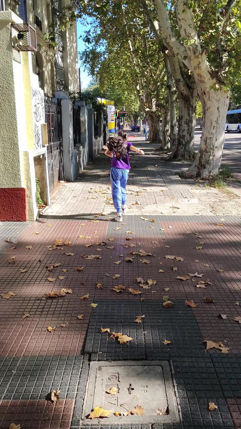 Vertical video of girl jumping on sunny sidewalk
