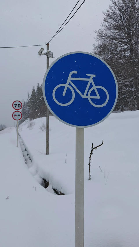 Bicycle lane road sign indicating a cycle path on a snowy day with heavy