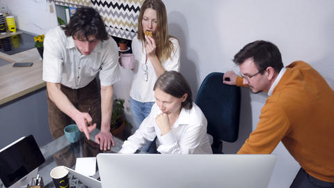 Office workers are discussing the morning news. A group of people is sitting at a table with a