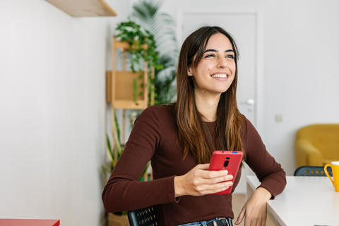Happy young beautiful woman using smart phone at home