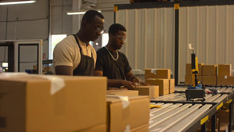 Workers assemble customer orders at a packing table in a warehouse, organizing boxes and preparing