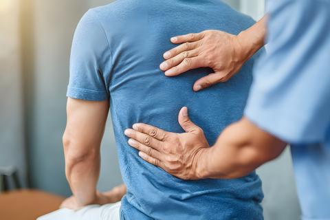 A male patient wearing a comfortable blue t shirt is receiving a professional back massage or physic