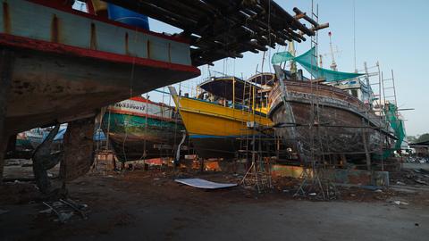 Fishing boats undergoing repair and maintenance at a shipyard in chumphon