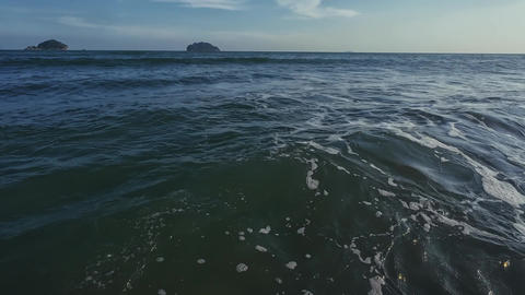 POV of bather looking out to sea as waves crash and submerge revealing