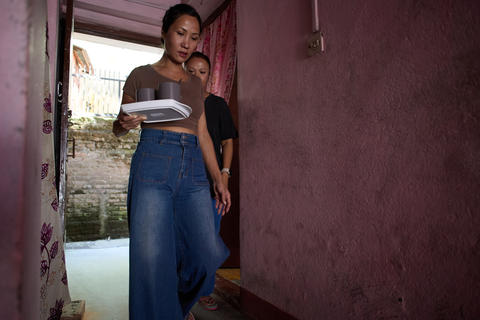 Two Women Navigating a Home Setting, One Carrying a Tray with Cups, Emphasizing